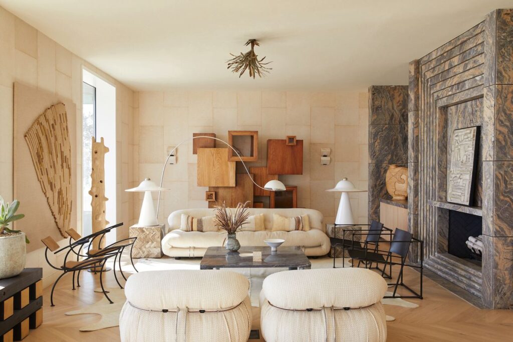 Curated living room with sculptural lounge chairs, layered textures, and symmetrical seating arranged around a marble fireplace.