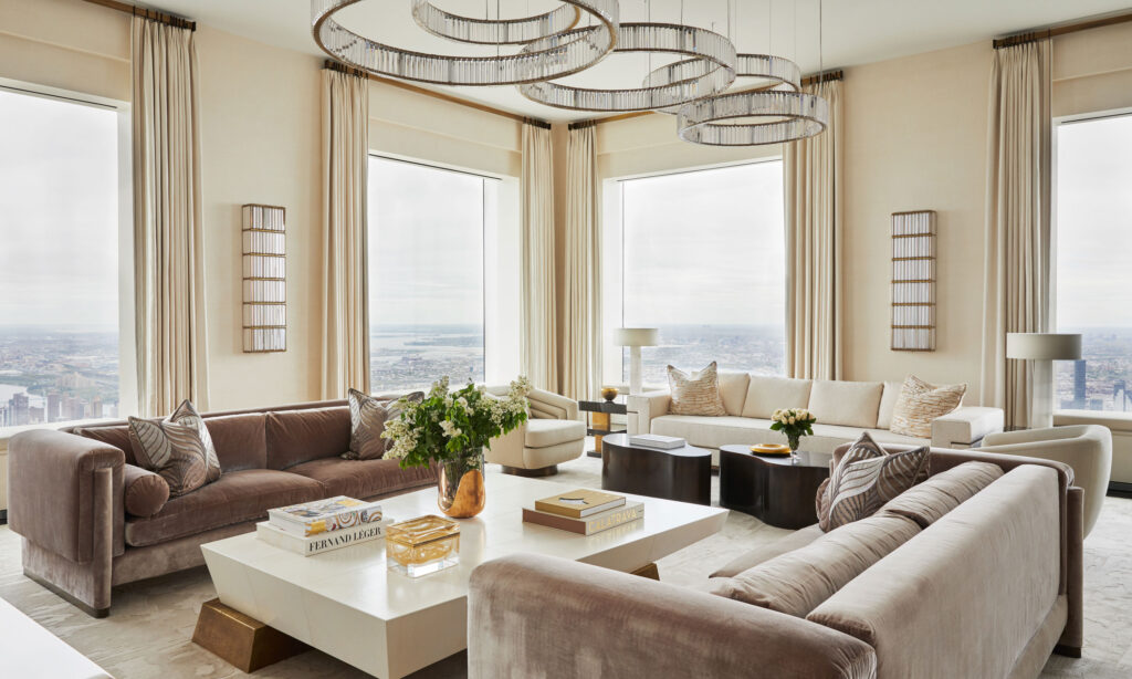 Luxurious open living room with multiple seating groups arranged symmetrically around a large coffee table and expansive floor-to-ceiling windows.