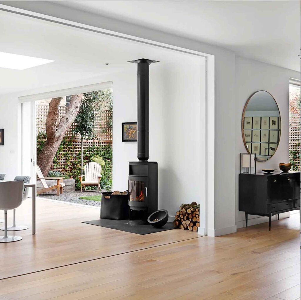 Bright open-plan living area with a modern wood-burning stove, wide sliding doors to the garden, and minimal Scandinavian-inspired décor.