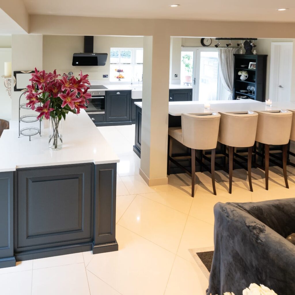 L-shaped open-concept kitchen with navy cabinets, white countertops, large island seating, and a spacious connected living and dining layout.