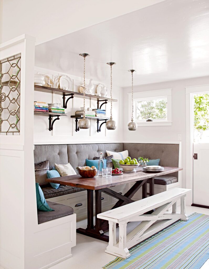 Built-in breakfast nook with upholstered bench seating, under-seat storage drawers, and open shelving, creating a cozy and multifunctional dining corner.