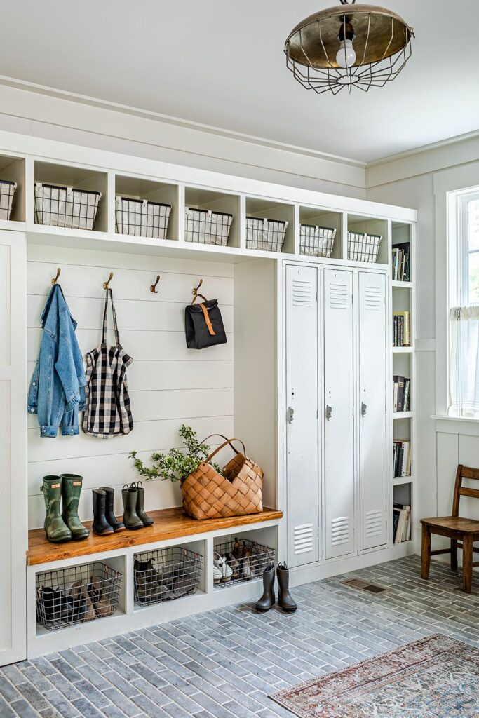 Bright farmhouse mudroom with built-in cubbies, lockers, hooks, baskets, and a wooden bench, showcasing organized shoe and coat storage.